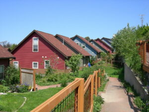 Credit for this image [red and blue houses in a row, with sidewalk, brown fence, and green grass in the foreground]: https://commons.wikimedia.org/wiki/File:Duwamish_Cohousing_03.jpg